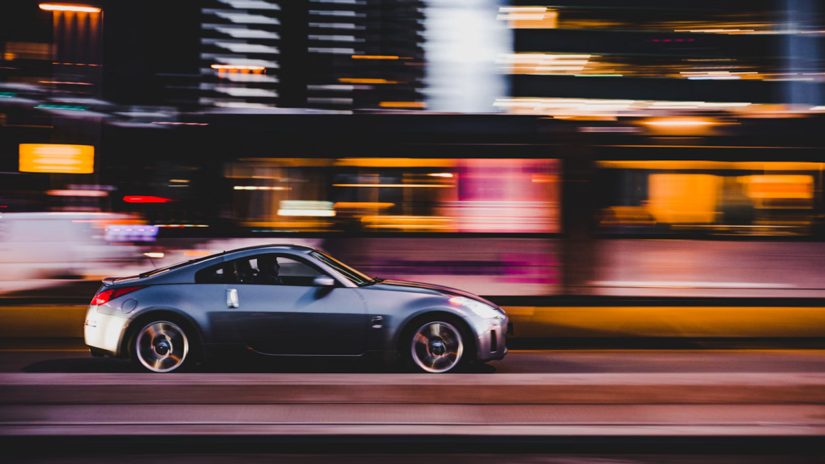 A car speeding down a road at night, with motion blur indicating high velocity and a sense of danger in the darkness.