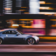 A car speeding down a road at night, with motion blur indicating high velocity and a sense of danger in the darkness.