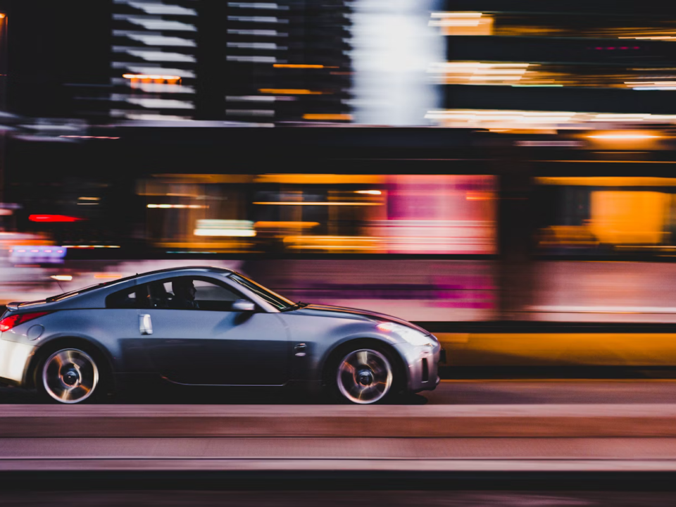 A car speeding down a road at night, with motion blur indicating high velocity and a sense of danger in the darkness.