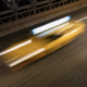 A blurred image of a car speeding across a bridge at night.