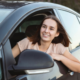 A smiling teenager driving a car.