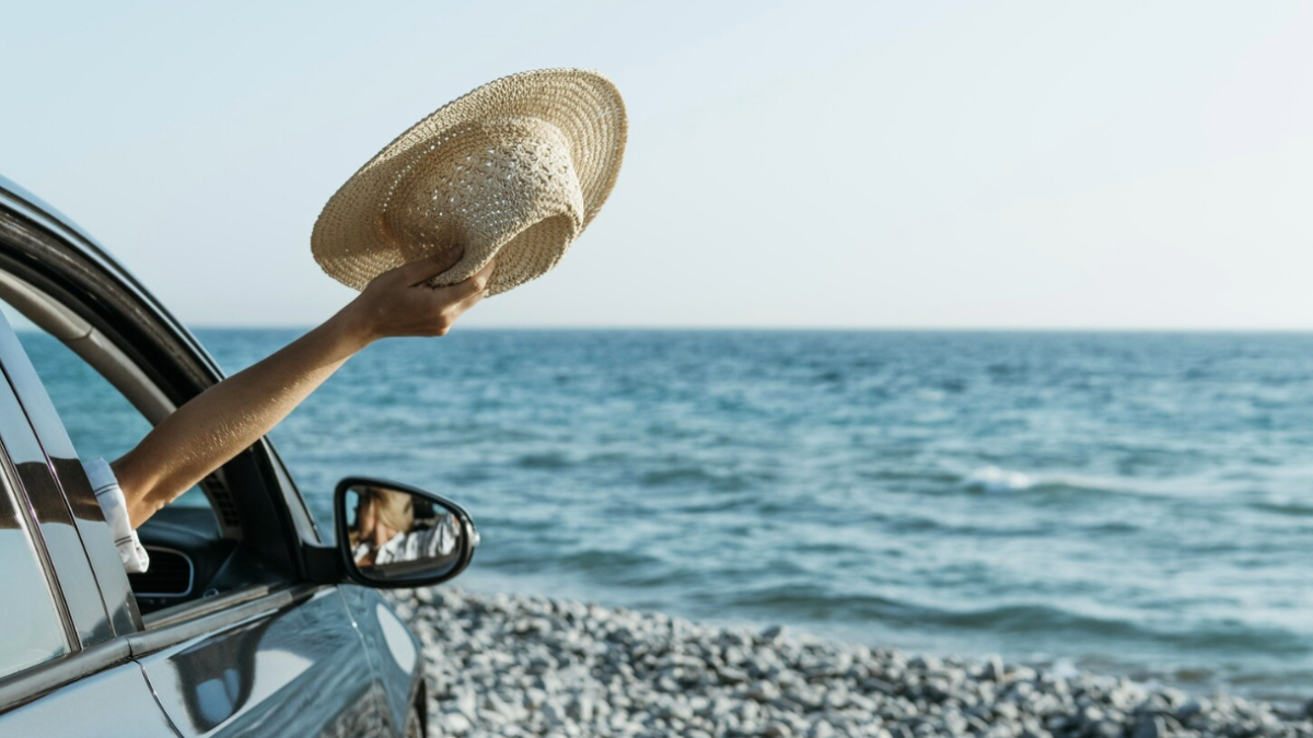 A car parked on a sandy beach with the ocean in the background.
