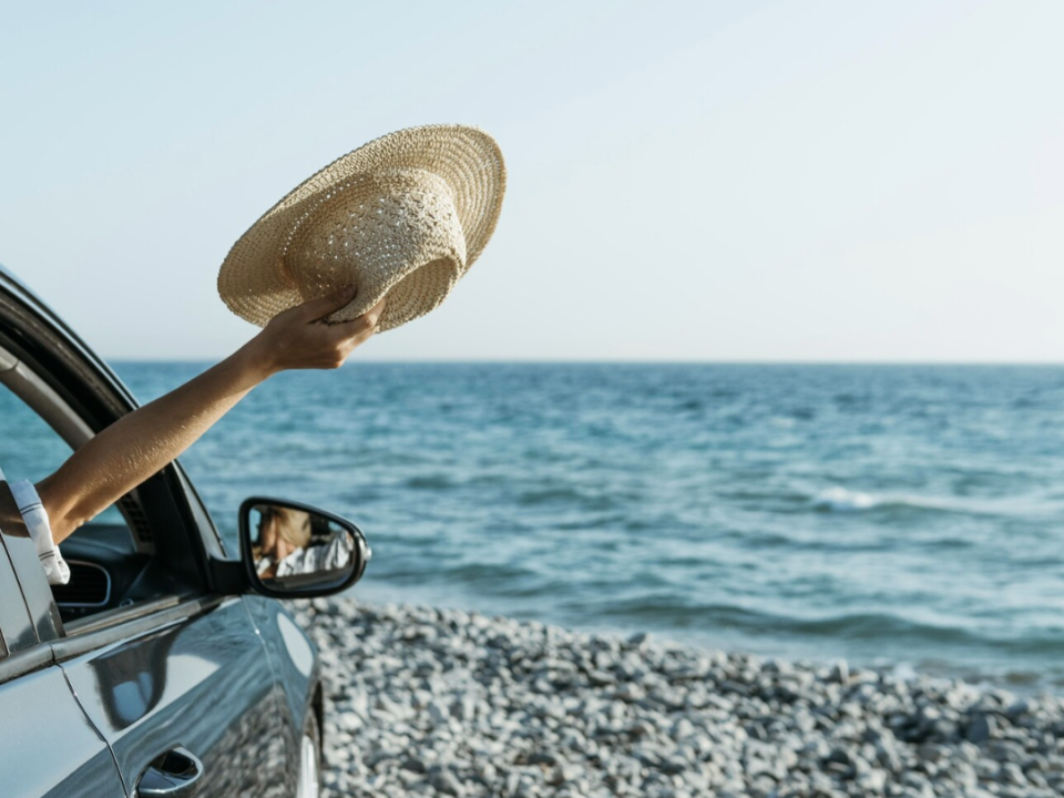 A car parked on a sandy beach with the ocean in the background.