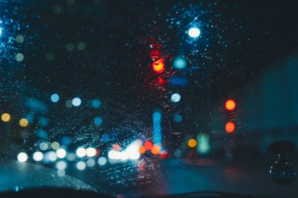 A rainy windshield with blurry lights on the other side