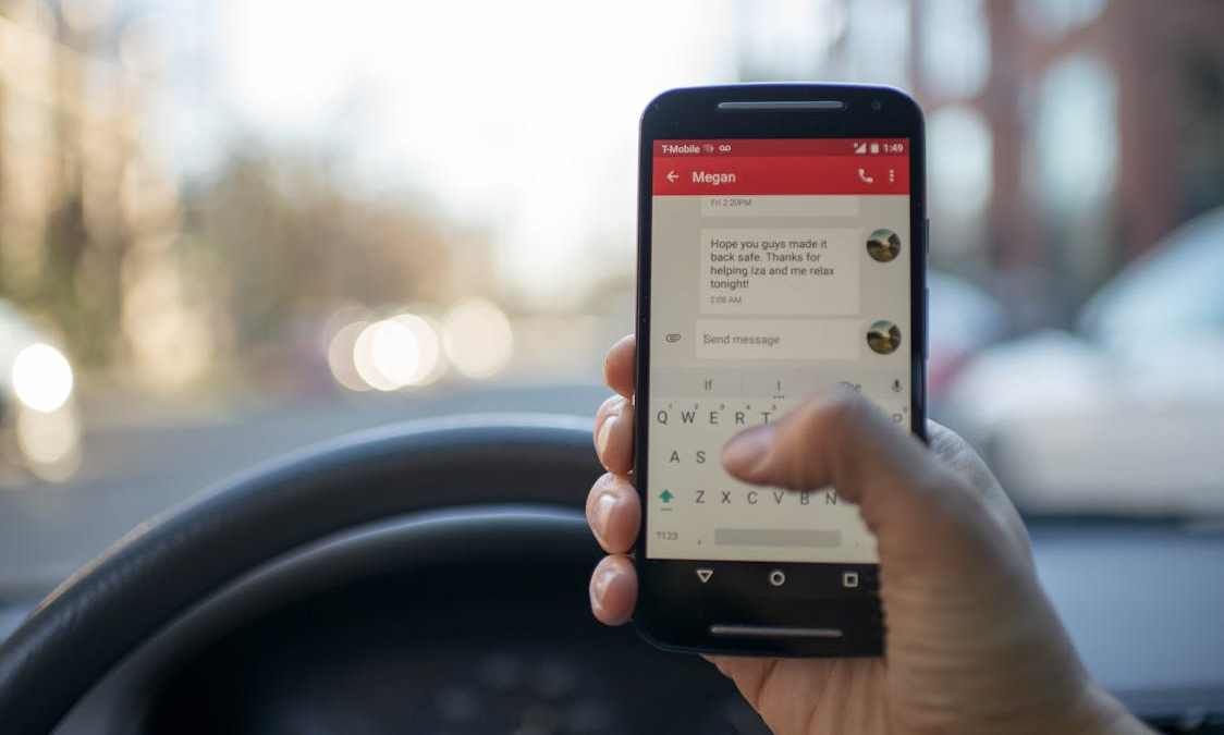 Driver holding a smartphone while sitting behind the wheel of a car