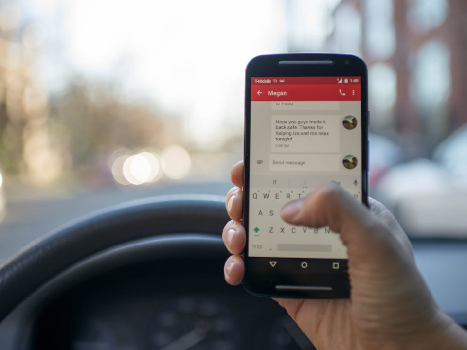 Driver holding a smartphone while sitting behind the wheel of a car